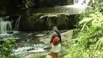 Busty babe masturbates by a tiny waterfall to fuck a dog